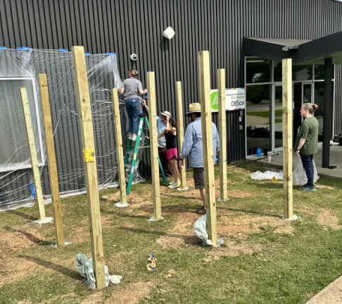 Teachers work on installing wooden poles.