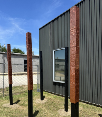 Three square columns covered in copper tiles with raised relief design