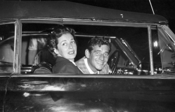 Black and white photo of a man and woman in a black car.